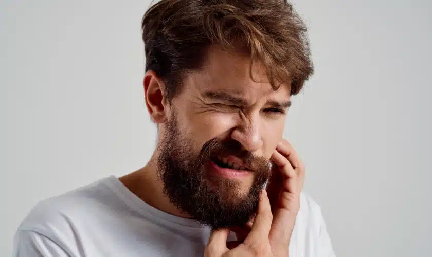 A man holding his jaw which is causing pain.