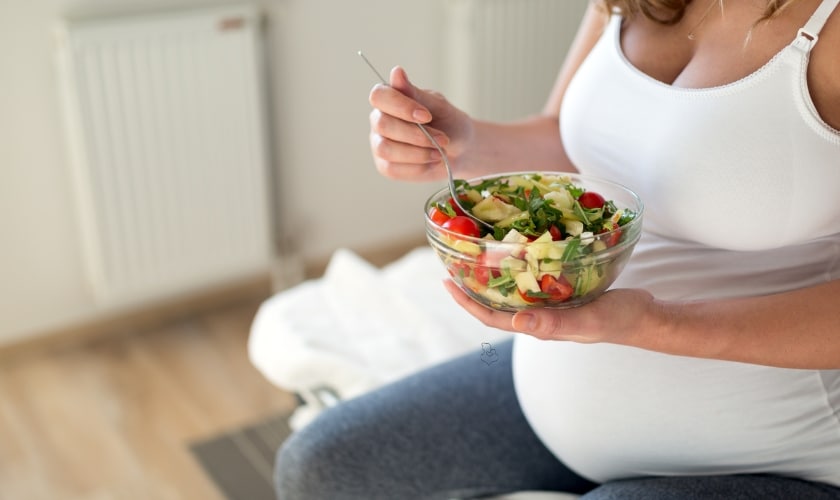 A pregnant lady eating fruits and veggies